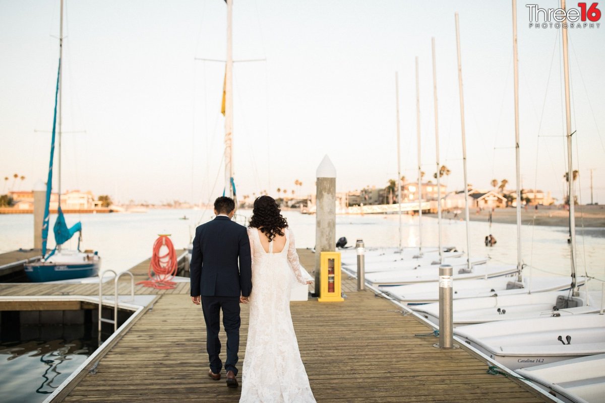 Bride and Groom walk away on the harbor deck