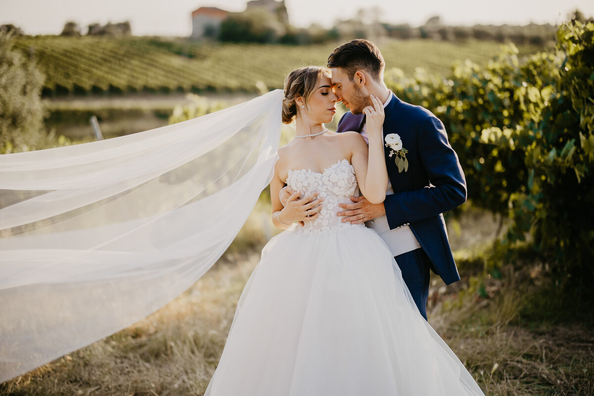 Bride and groom embracing with flowing veil in Chianti vineyards, Castello il Palagio wedding photographer Tuscany.