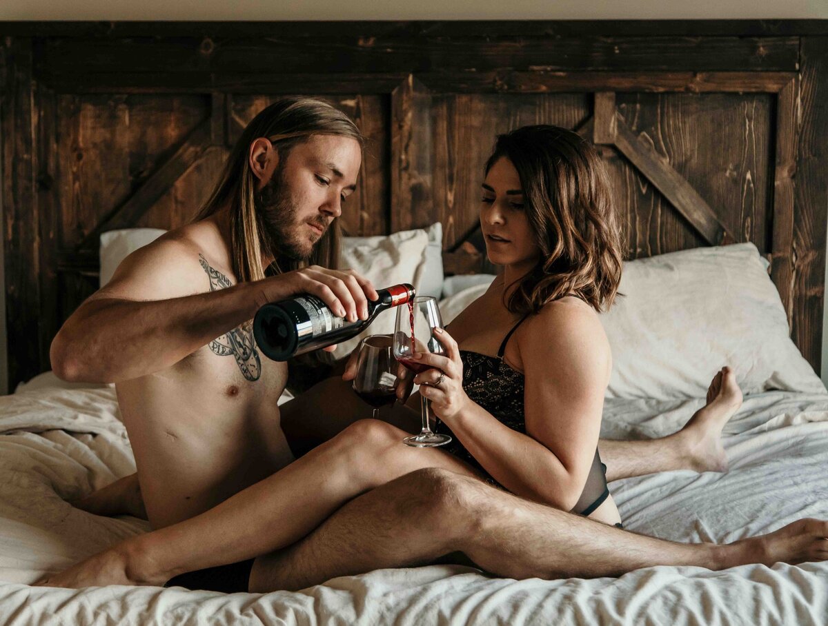husband and wife sharing a glass of wine during couples boudoir shoot