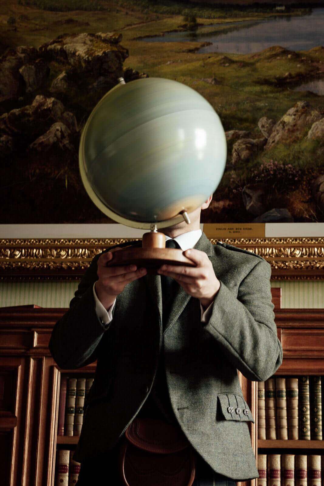 a groom holds a globe in front of his face while it spins