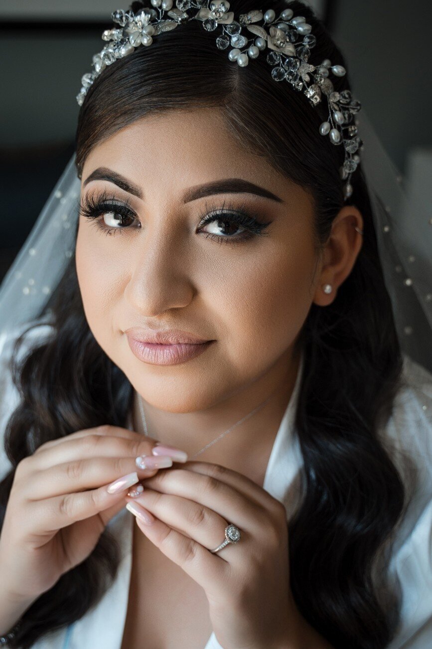 Bride securing her necklace and looking into the camera during wedding prep at The Union Club Hotel at Purdue University.