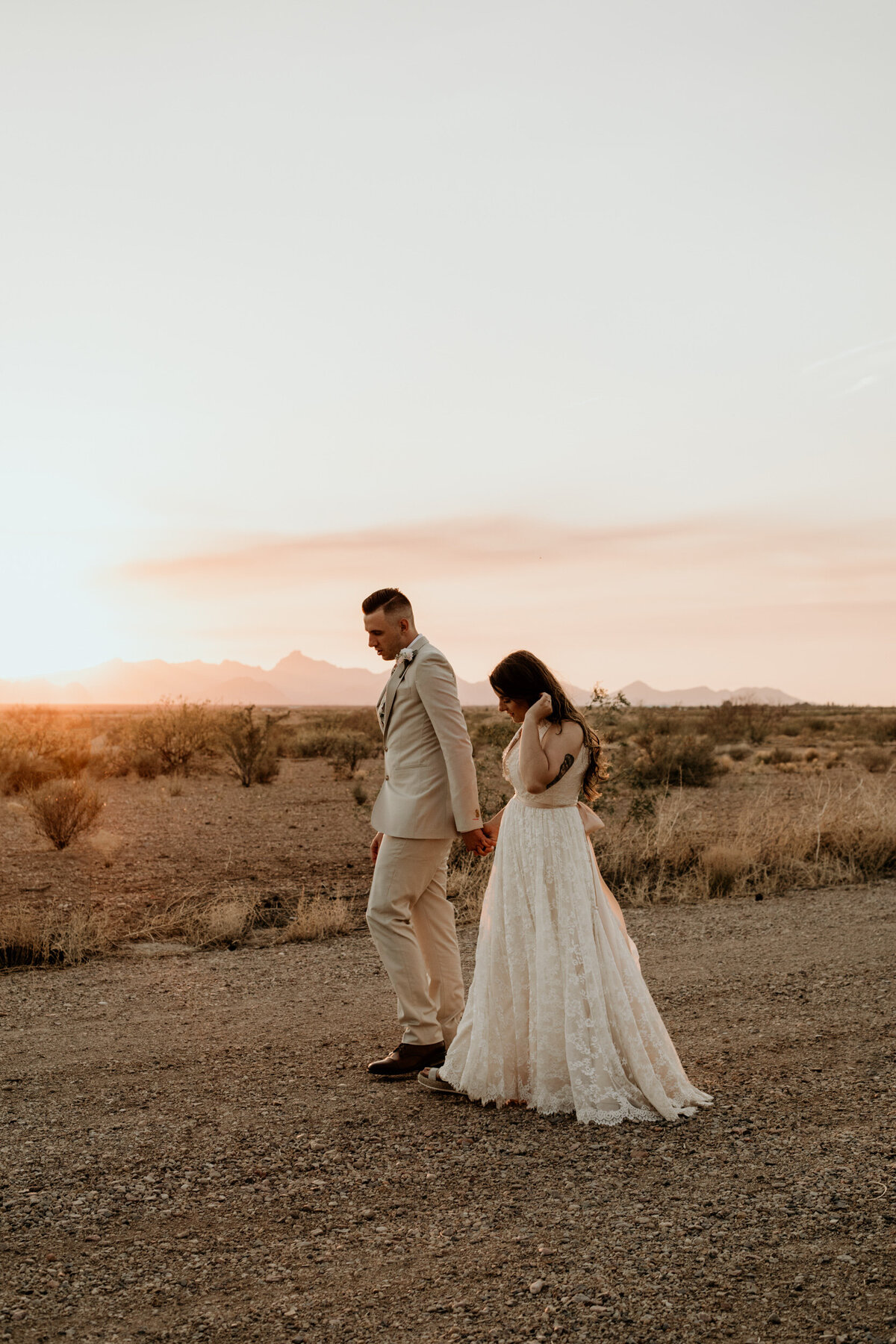 bride and groom walking in the desert together at sunset
