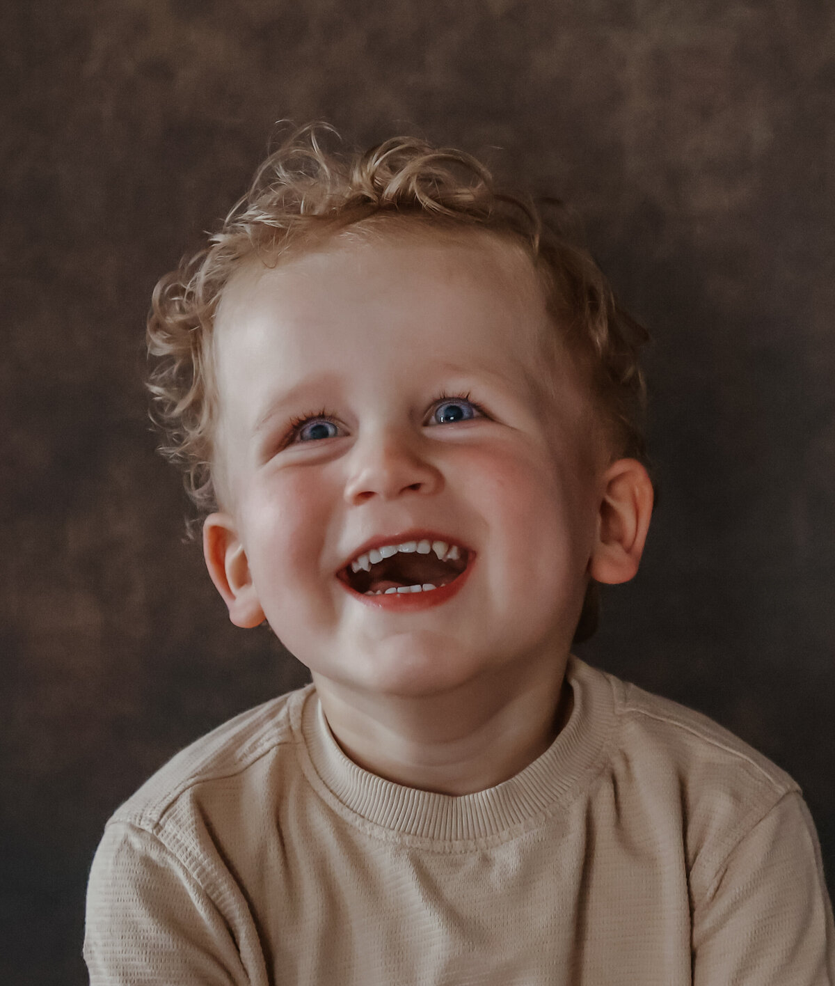 close up portret van lachend jongetje, kijkt naar boven