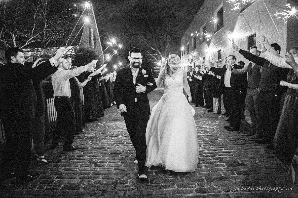 A married couple walking through a tunnel of their guests holding sparklers.