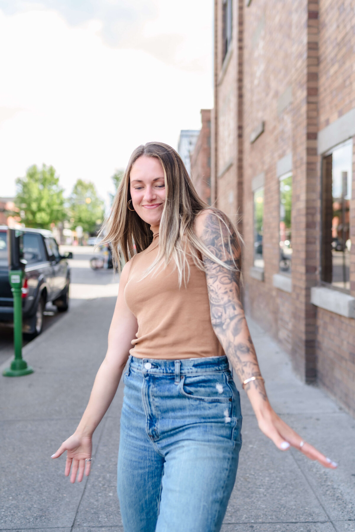 Carefree woman walking down the street in tan shirt and jeans for creative portrait