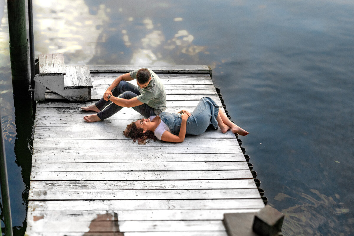 Salem VA wedding and Elopement photographer earthy and moody Charleigh Roberts Photography artsy earthy moody virginia roanoke va east coast enagagment session couples dock water lake candid denim laying on the dock