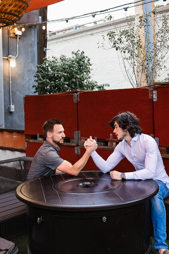 Two men arm wrestle at their party.