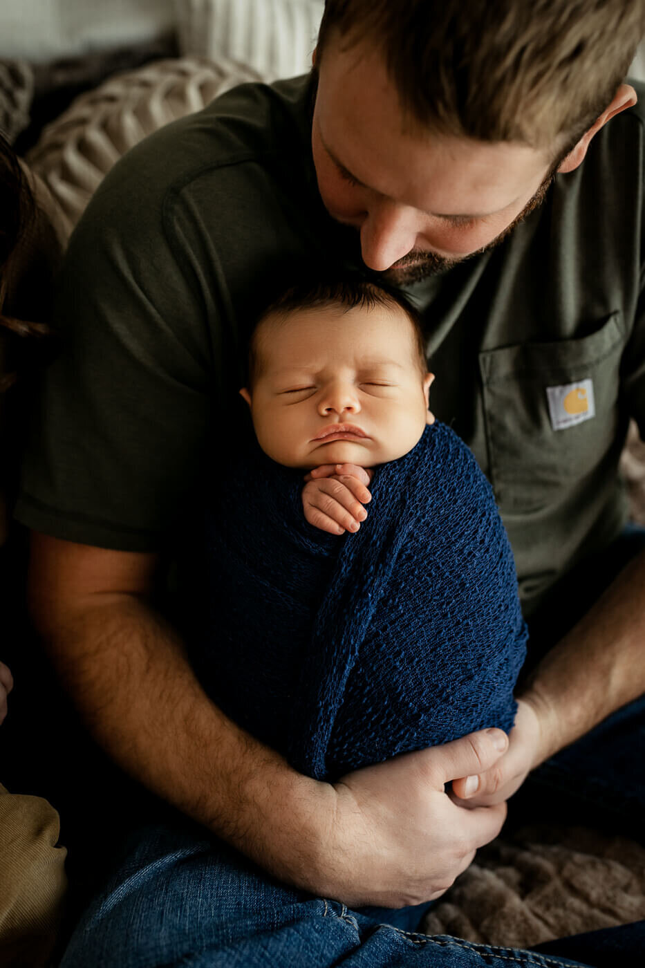 Dad snuggling newborn baby wrapped in blue