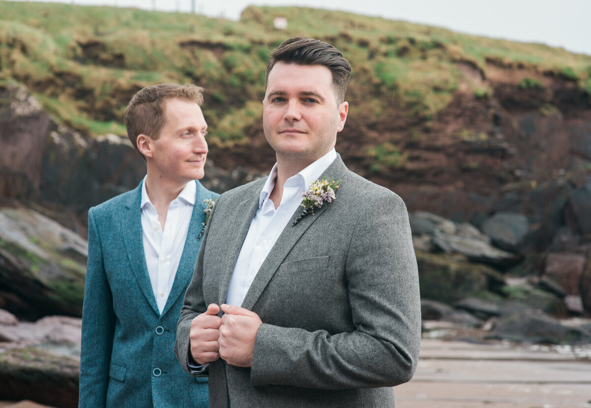 gay wedding couple standing on beach