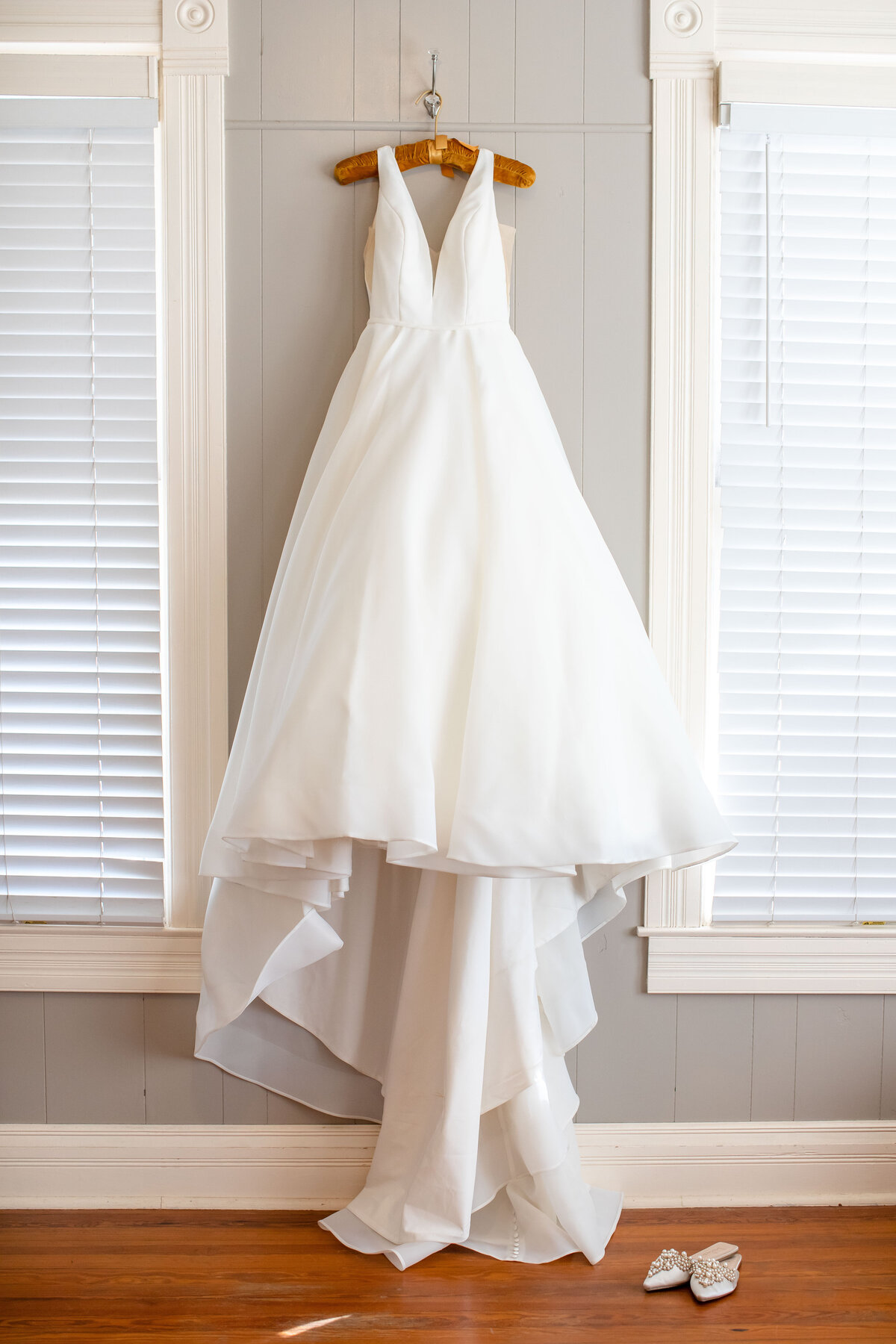wedding gown on velvet hanger hangs between two windows at Allen Farmhaus in New Braunfels Texas