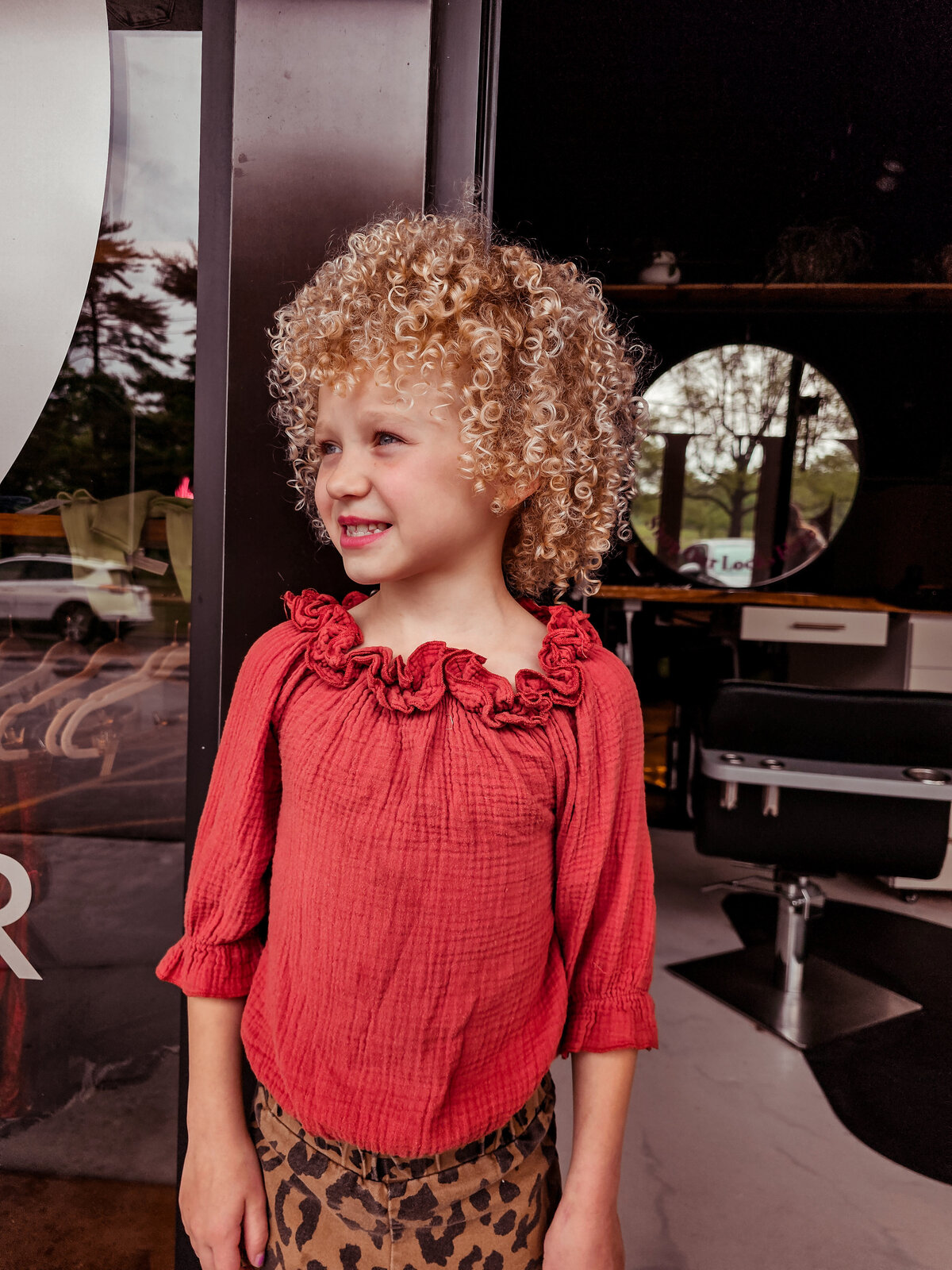 An adorable little blonde haired, tight curly hair little kid's cut from Moxie by KC