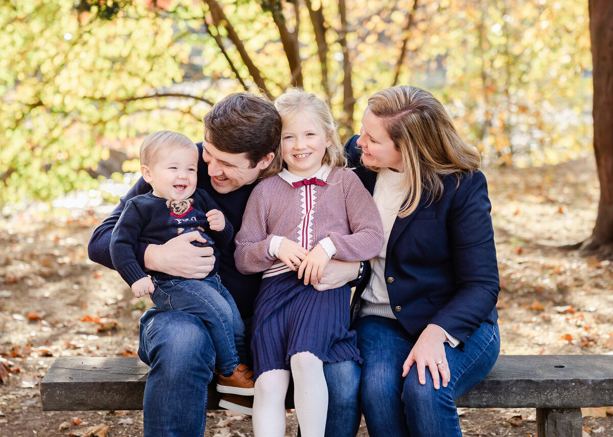 Lifestyle photo of family hugging on a bench at a NJ park in the fall.