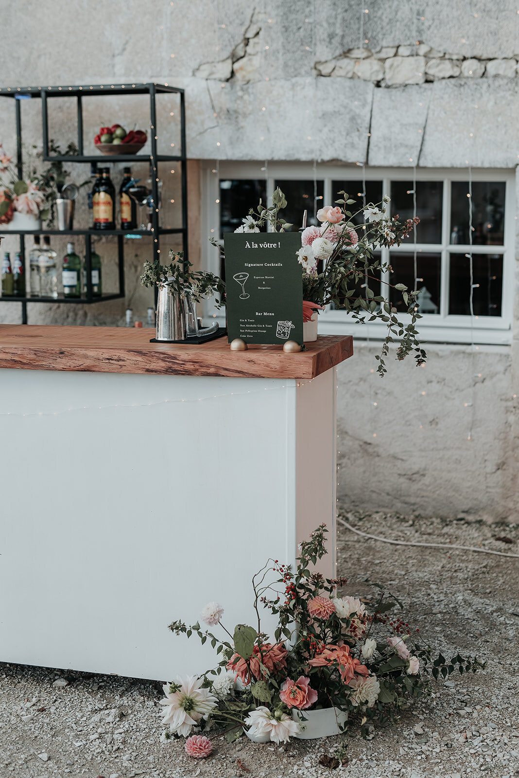 Delicate pink and white floral arrangements on an outside bar at a wedding in France