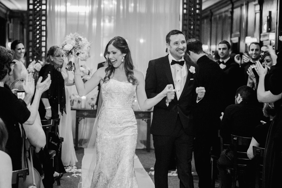 Newlyweds walk down the aisle together as their loved ones cheer for them