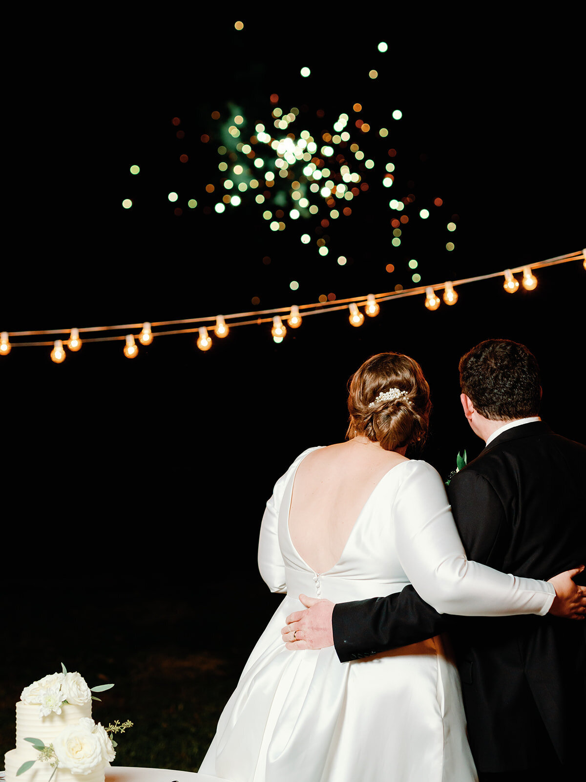 Bride and groom watch the fireworks light up the sky