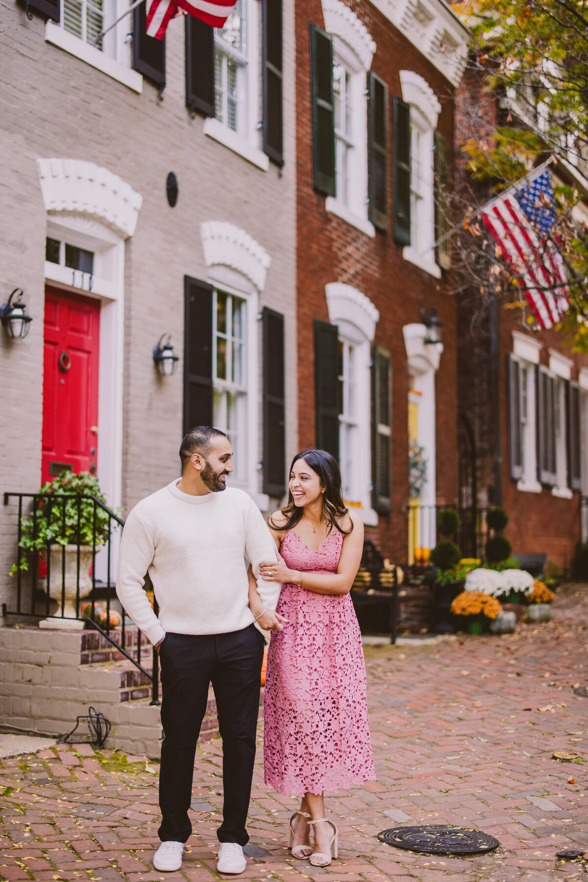A couple laughing during their engagement session on a historic street in old town alexandria maryland