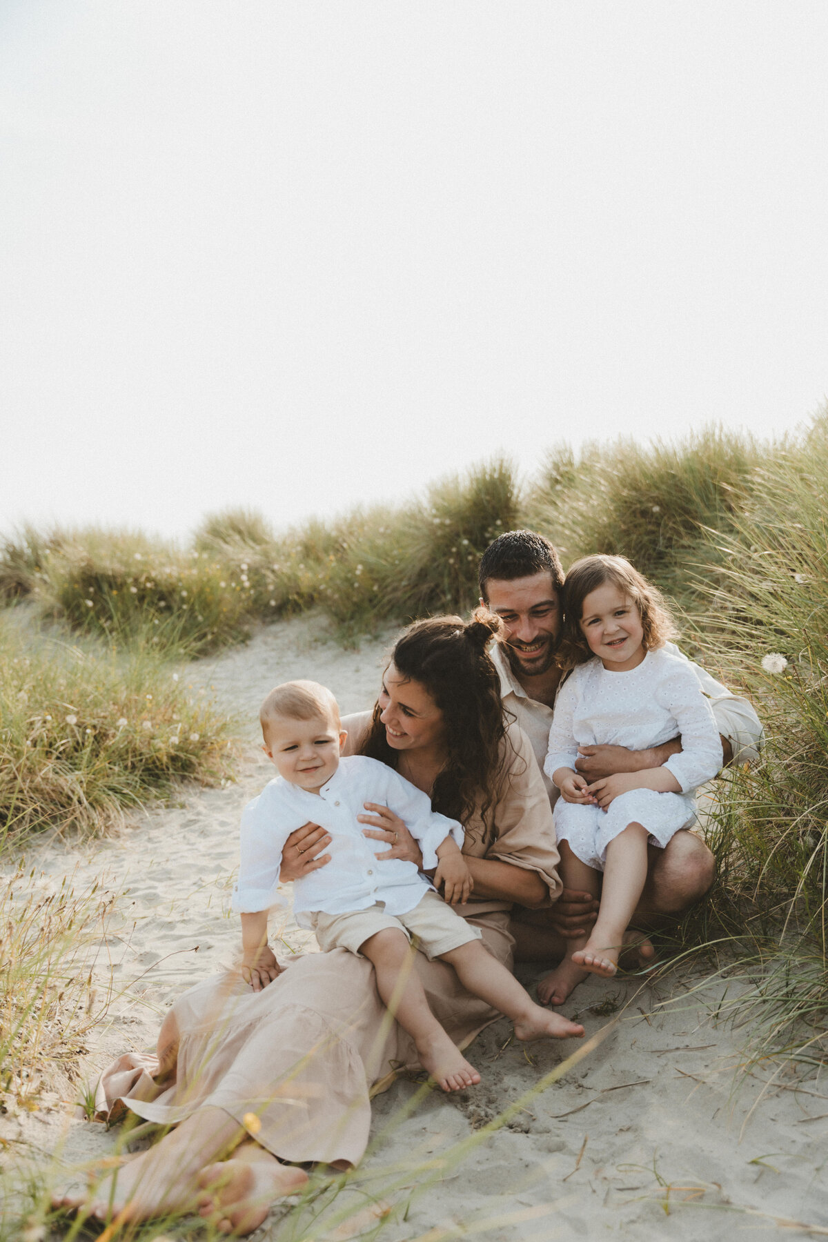 Ouders knuffelen met zoon en dochter in de duinen.