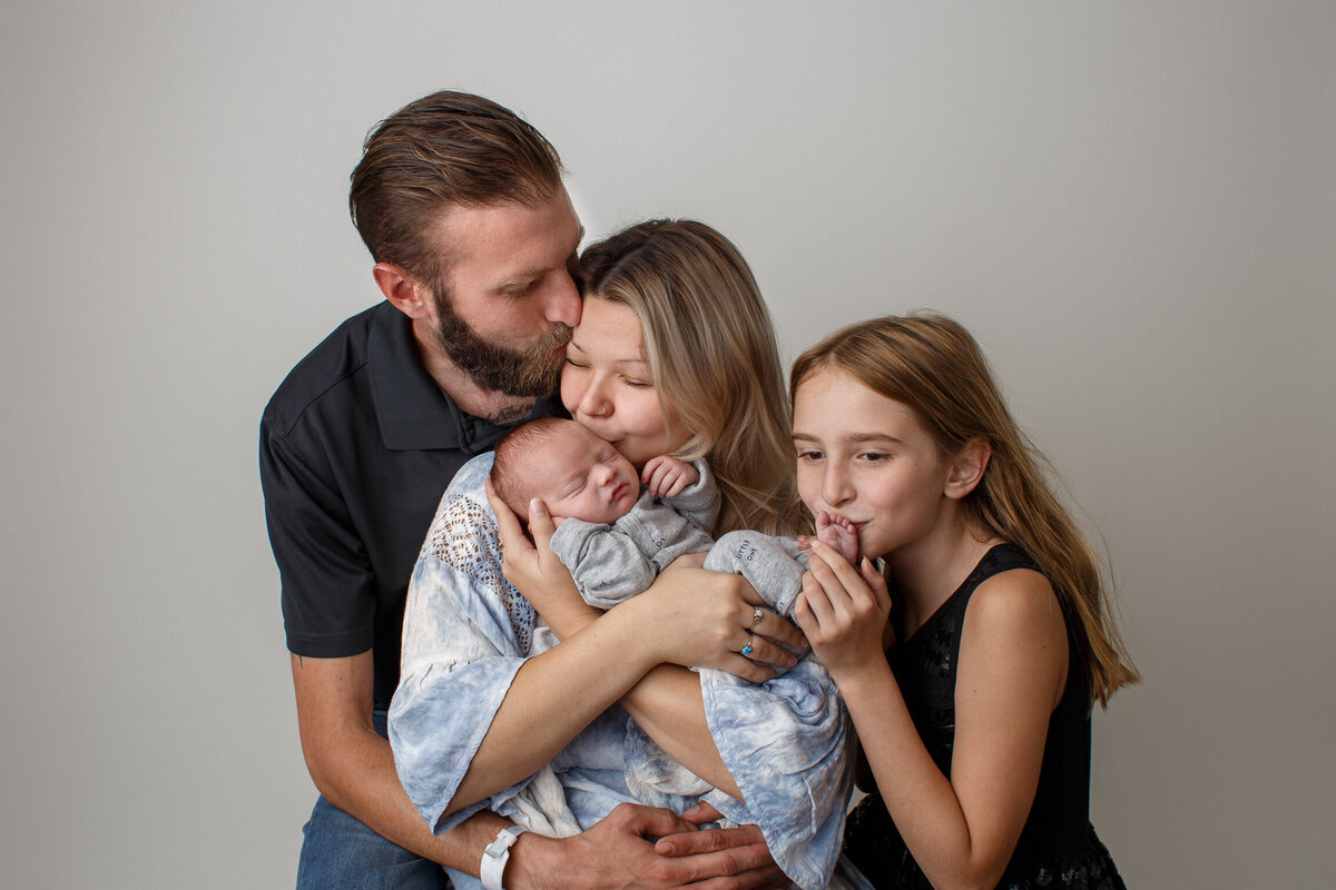Beautifulportrait of a  young family with their newest baby photographed on a white background by newborn photographer