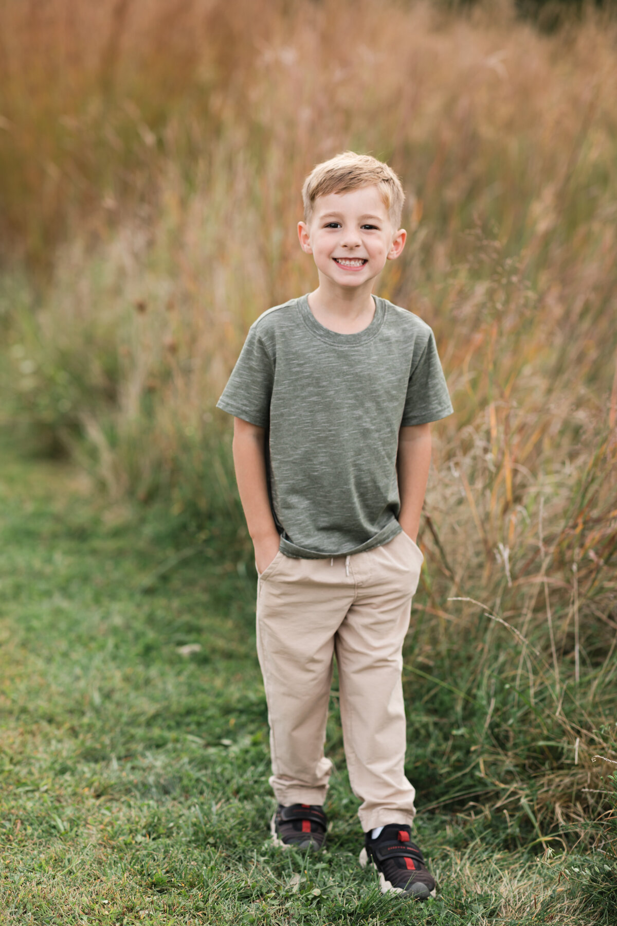 boy in green shirt and khakis' posing for family portraits