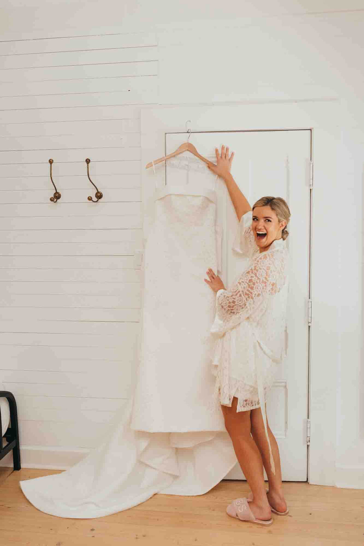 bride is excited to be getting into her wedding gown soon, as it hangs on the door.