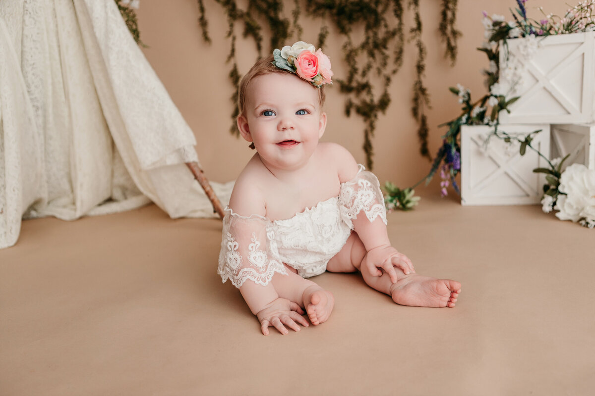 child sitting in lace outfit with floral headband