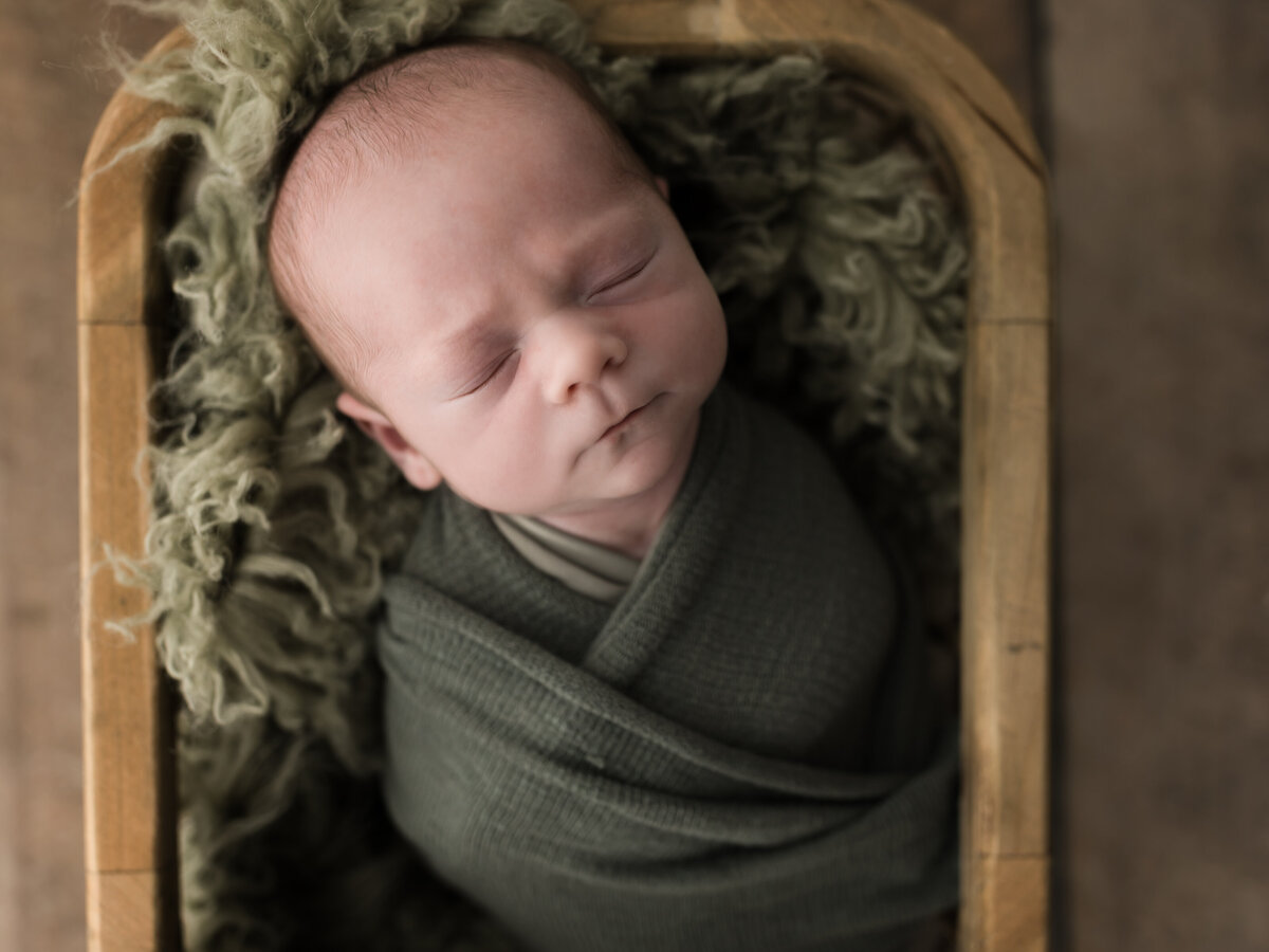 newborn baby boy wrapped in green swaddle for studio newborn portraits cleveland newborn photographer 