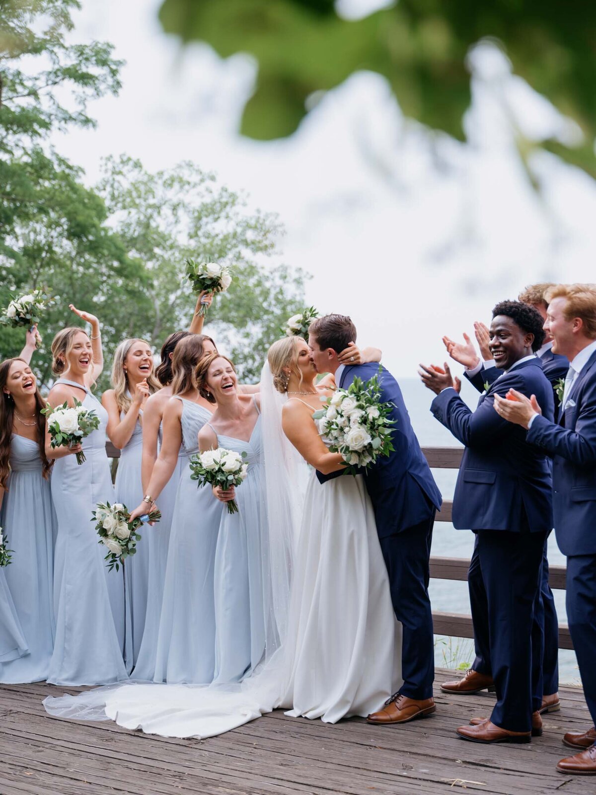 Bridal party with couple kissing by the water at the Cleveland Yachting Club