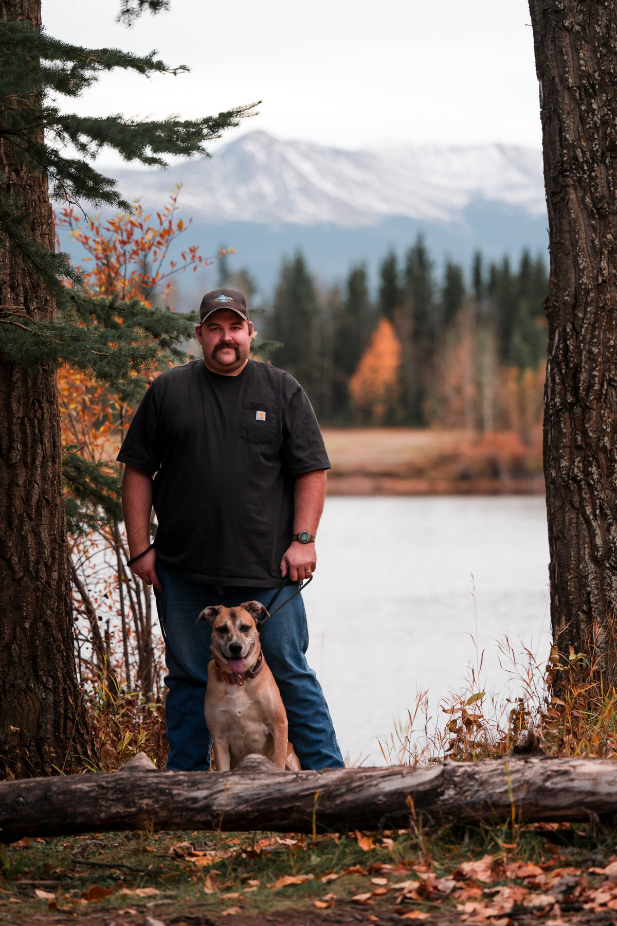 man and dog pose for photos in the mountains