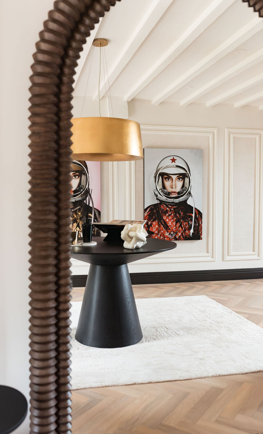 A mirror reflection shows artwork on the opposite side of the modern foyer, featuring female astronauts.