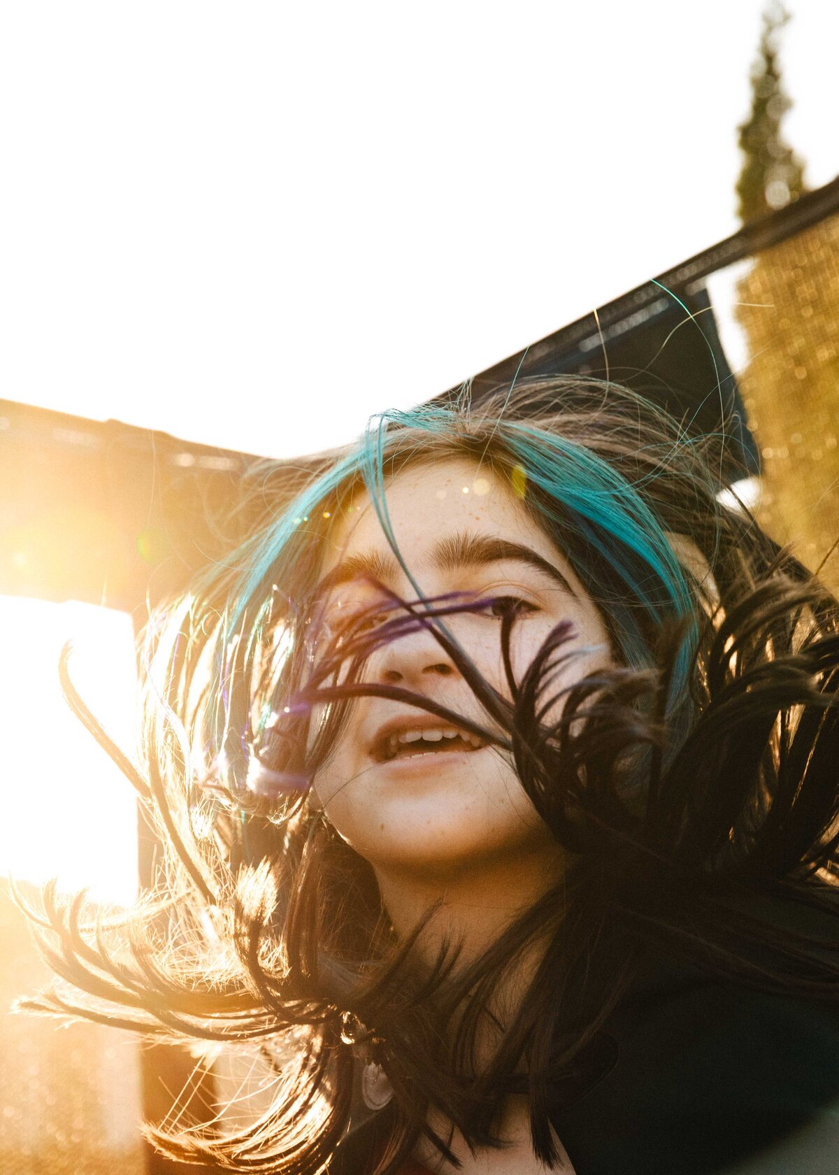 Teenager is jumping on a trampoline with wild hair. 