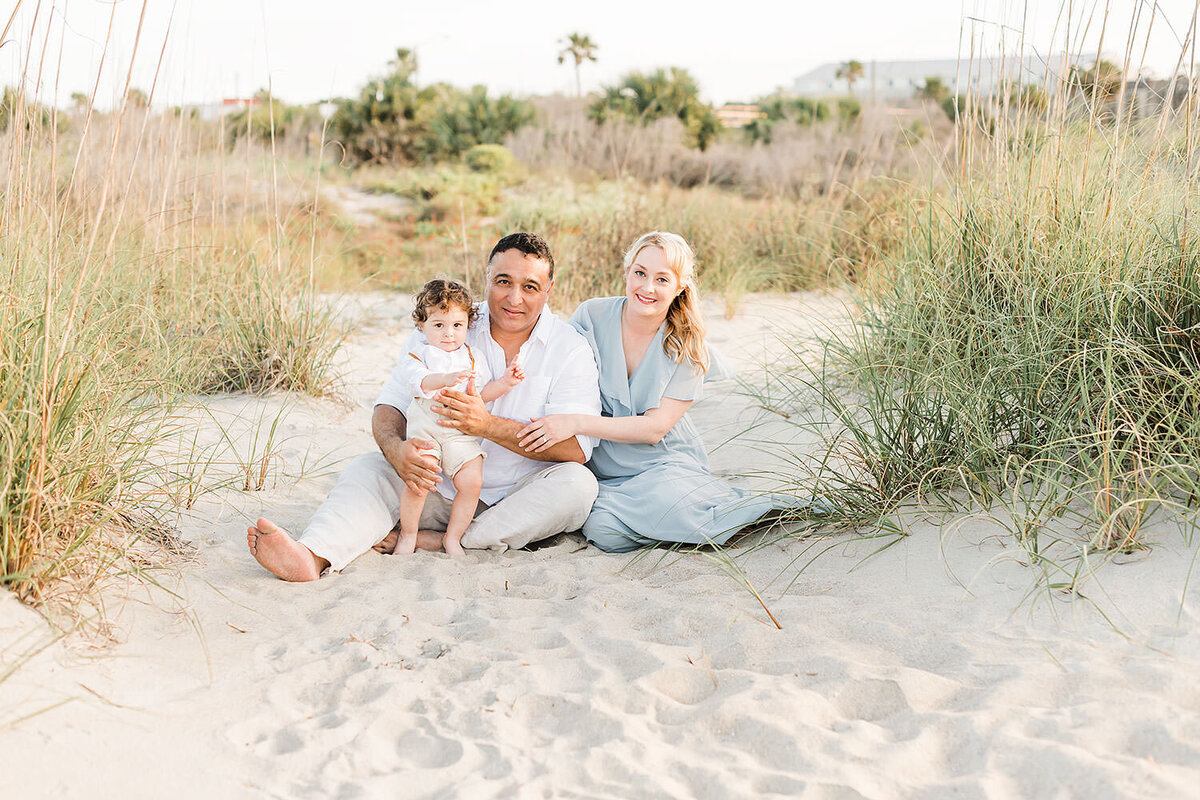 a beautiful family sitting on  a soft beach for a Destin photo session