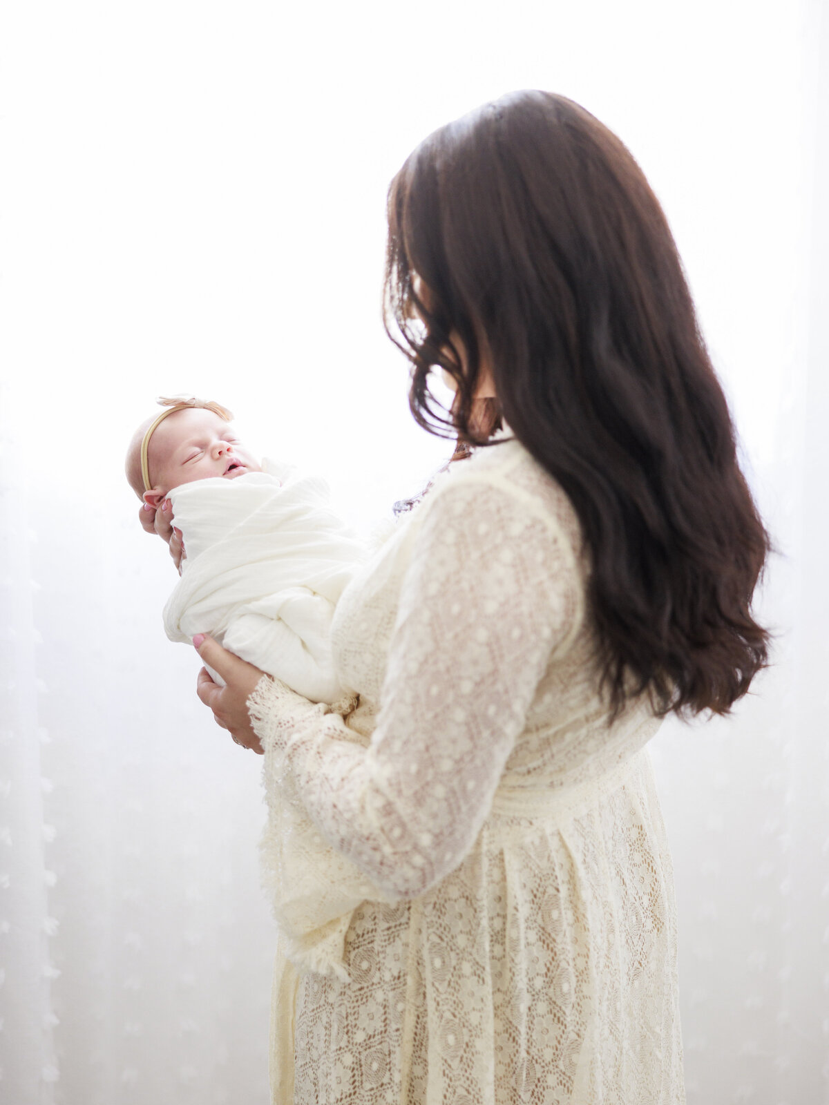 mom looking at swaddled baby for Tampa newborn photographer Tina Marie Studio.