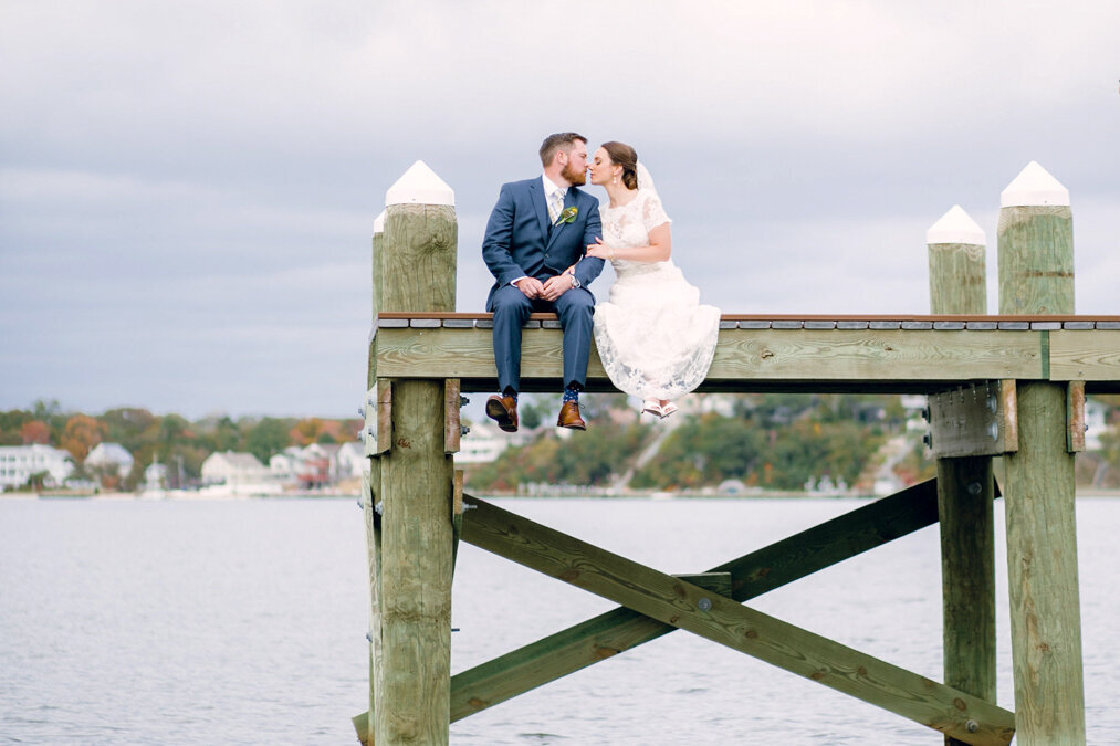 A bride and groom kissing on a dock.