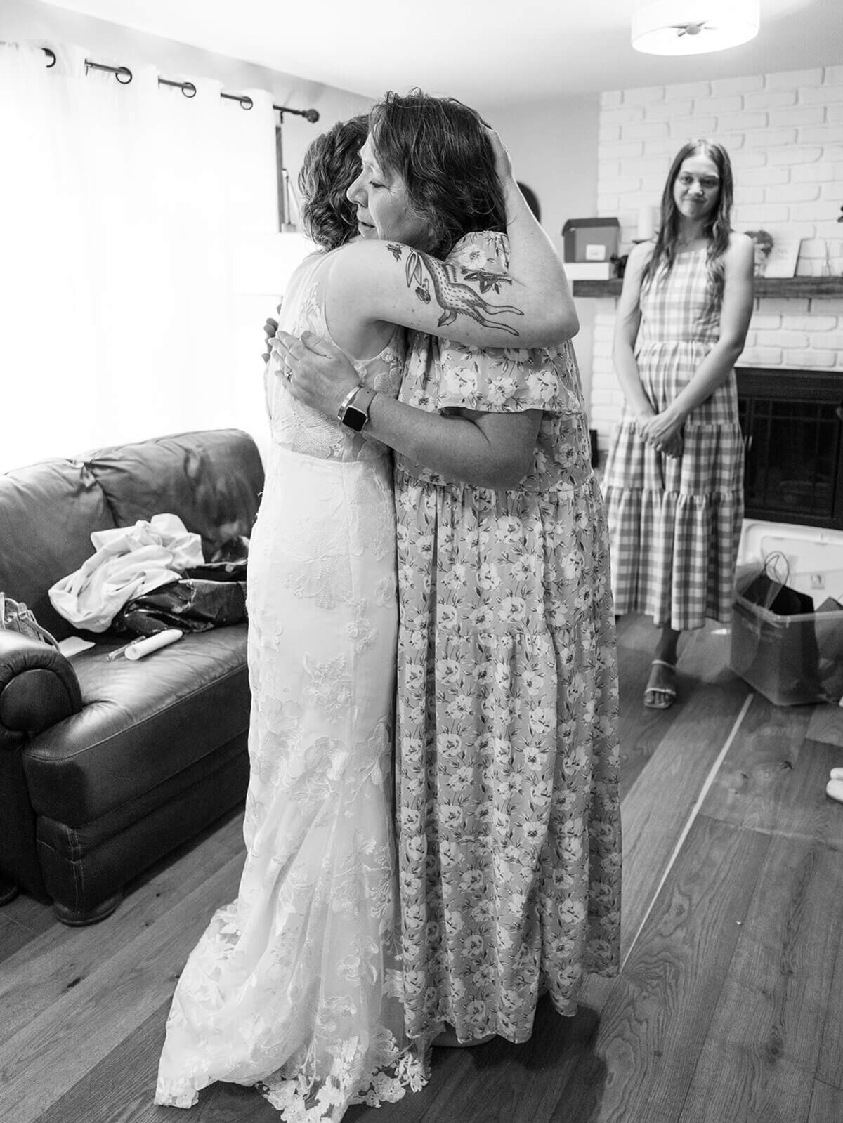 A bride embraces a loved one in her home. 