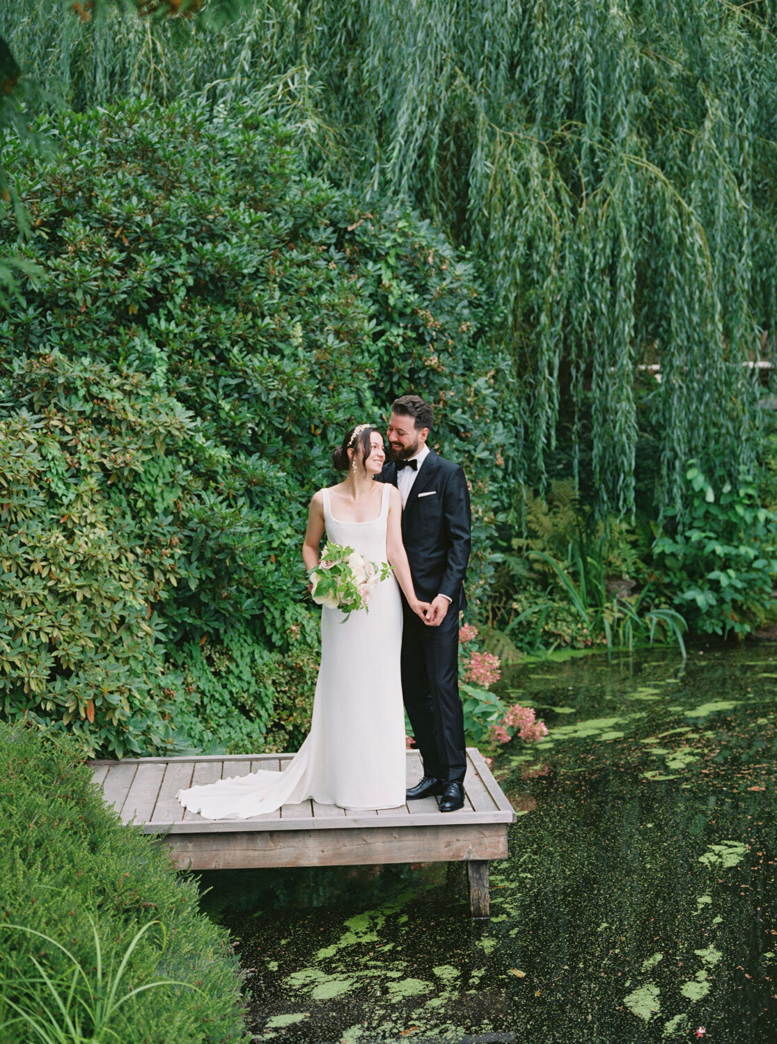 Couple standing on a wooden dock by greenery