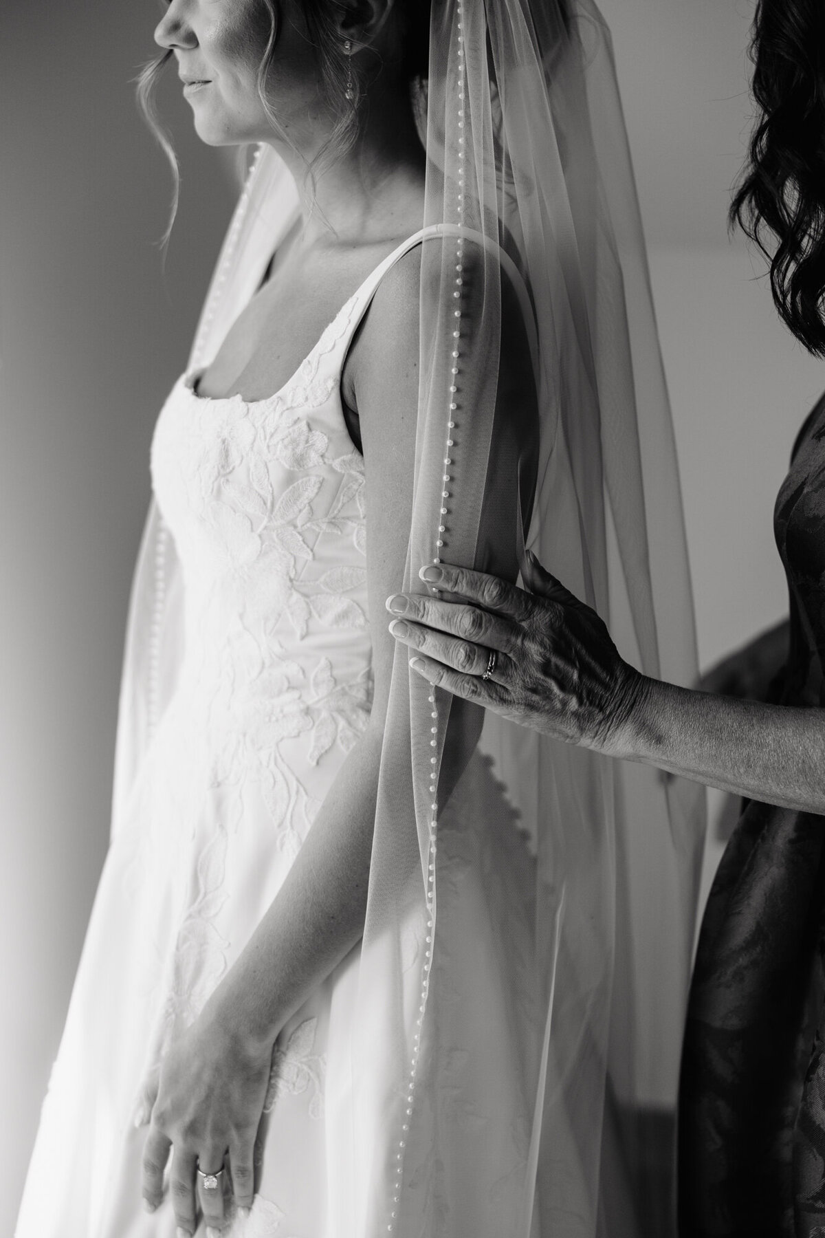 Candid moment of bride getting zipped into wedding dress by mom