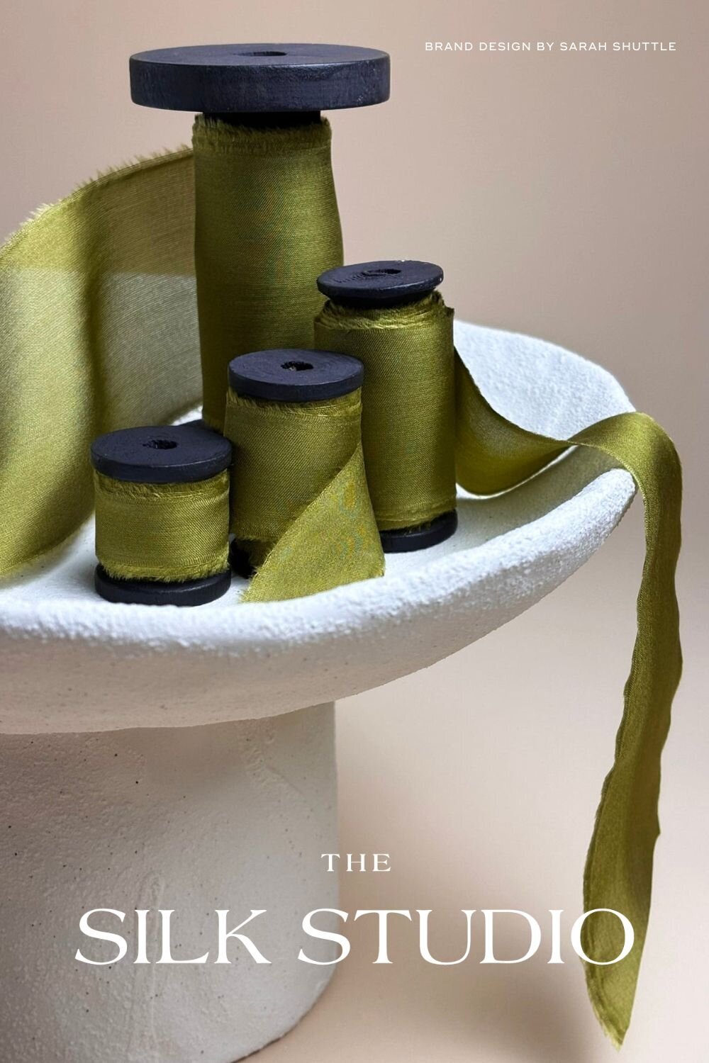 Spools of hand-dyed green silk ribbon with The Silk Studio logo in view