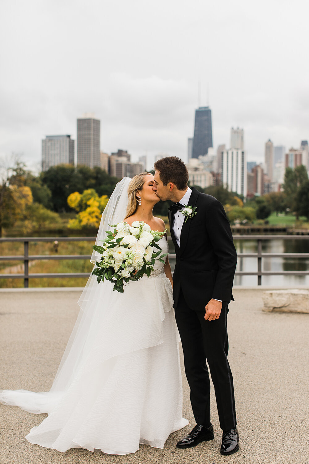 A bride and groom share a kiss with the Chicago skyline in the backdrop