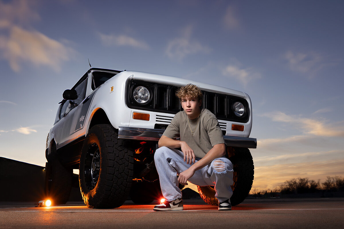 A senior sits beside his rugged vintage truck, captured in dynamic Dallas senior photography.