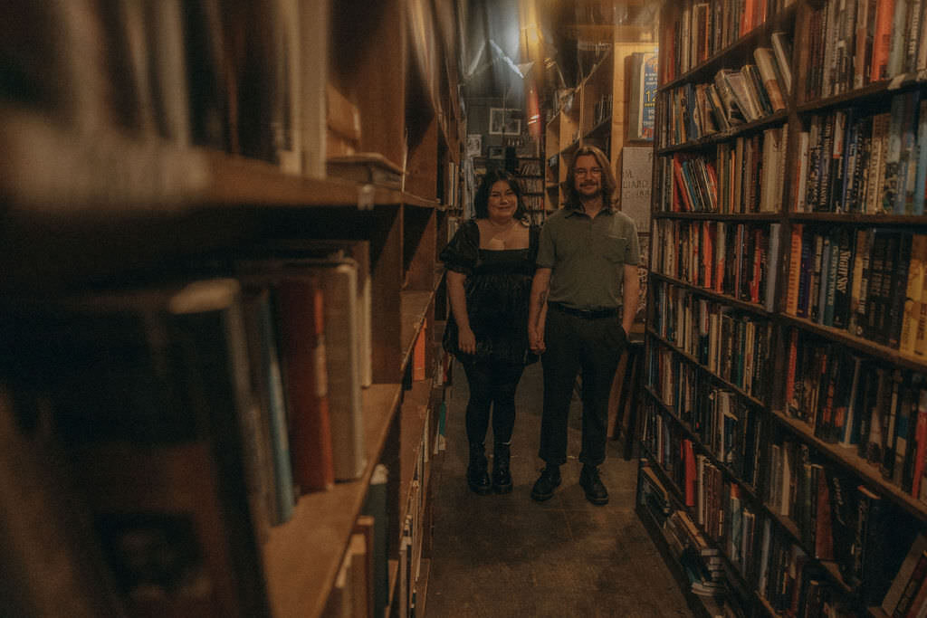 A couple holding hands while standing in a bookstore.