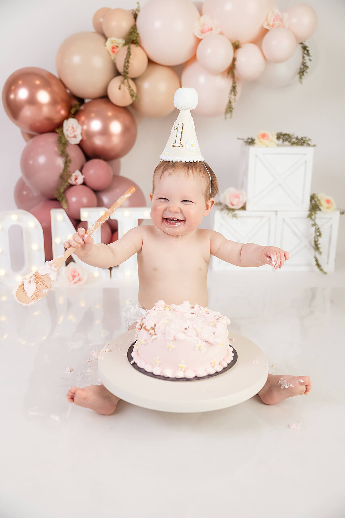 Baby girl having fun with her cake during her birthday cake smash session at Jennifer Brandes Photography studio.