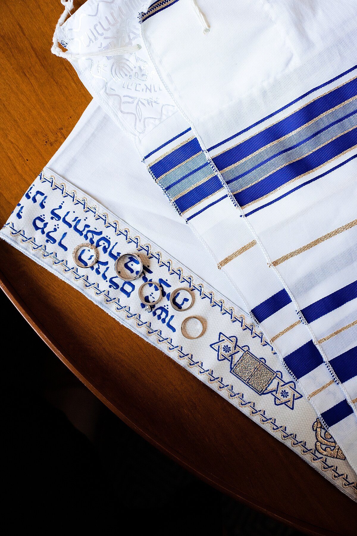 Blue and white tallit with gold wedding and engagement rings