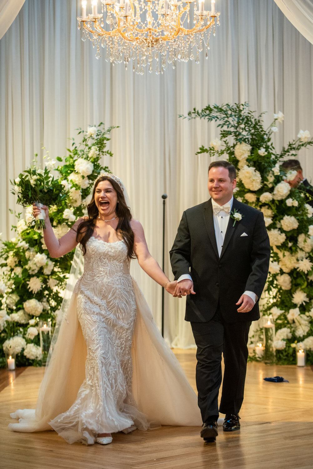 A bride and groom are walking down the aisle holding hands