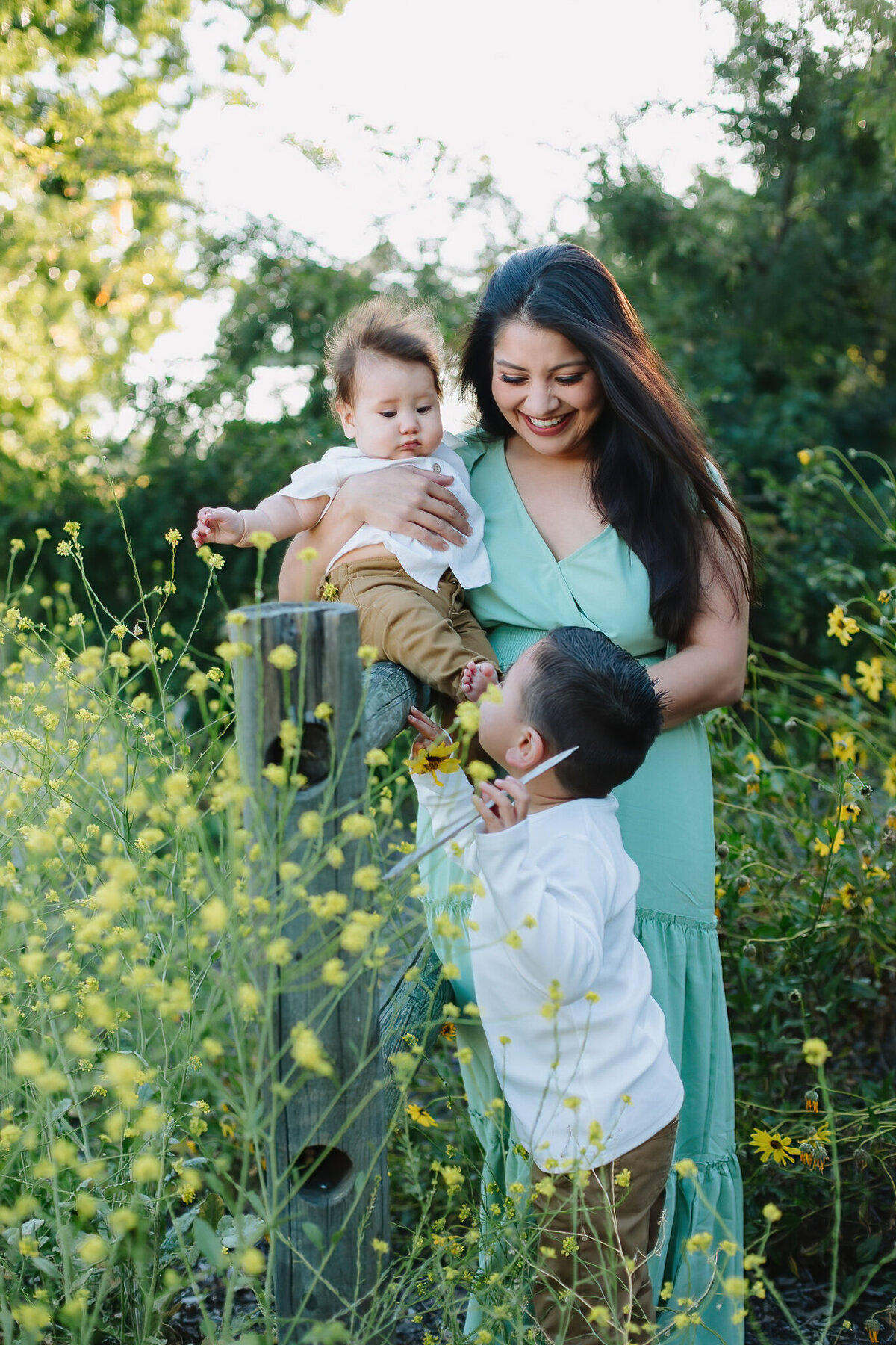 Mom holdiMom in flower field with her small children at Willow Springs Park