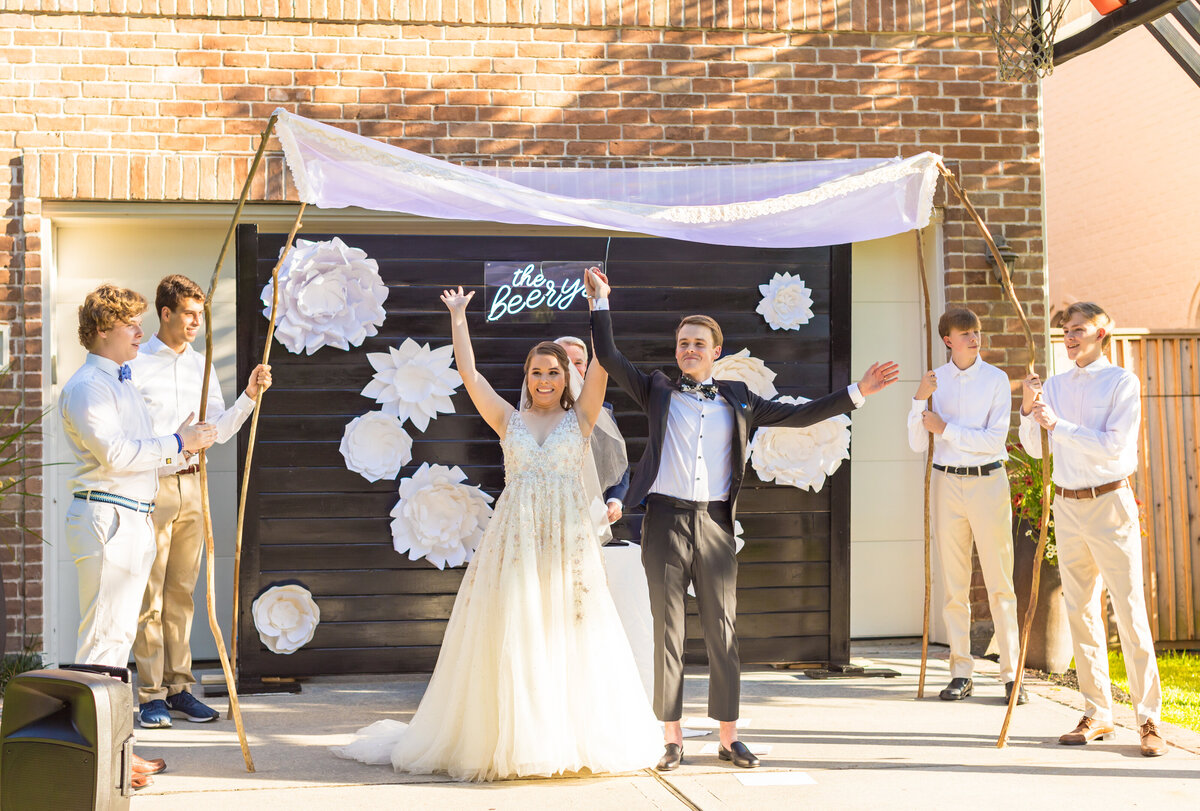 Bride and groom at wedding ceremony in front of a black backdrop display with large white florals