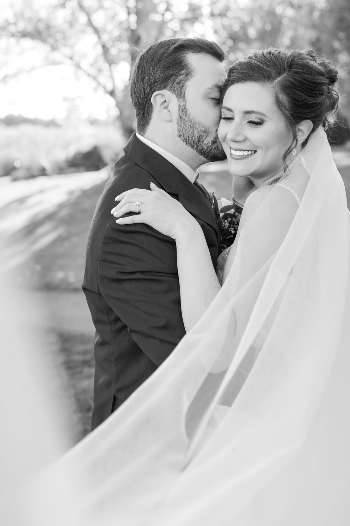 Bride and groom snuggle up with a swooping veil