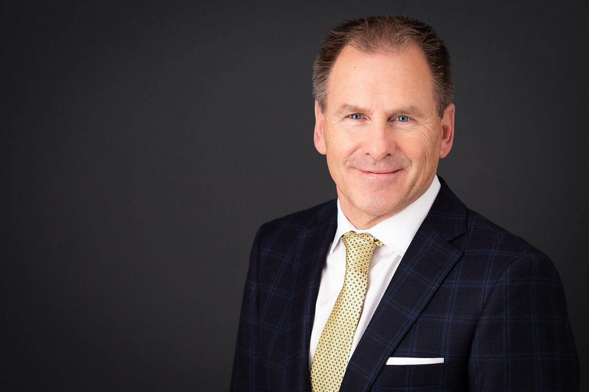 an in-studio headshot of a male in a blue suit against a charcoal backdrop taken by Ottawa Headshot Photographer JEMMAN Photography Commercial