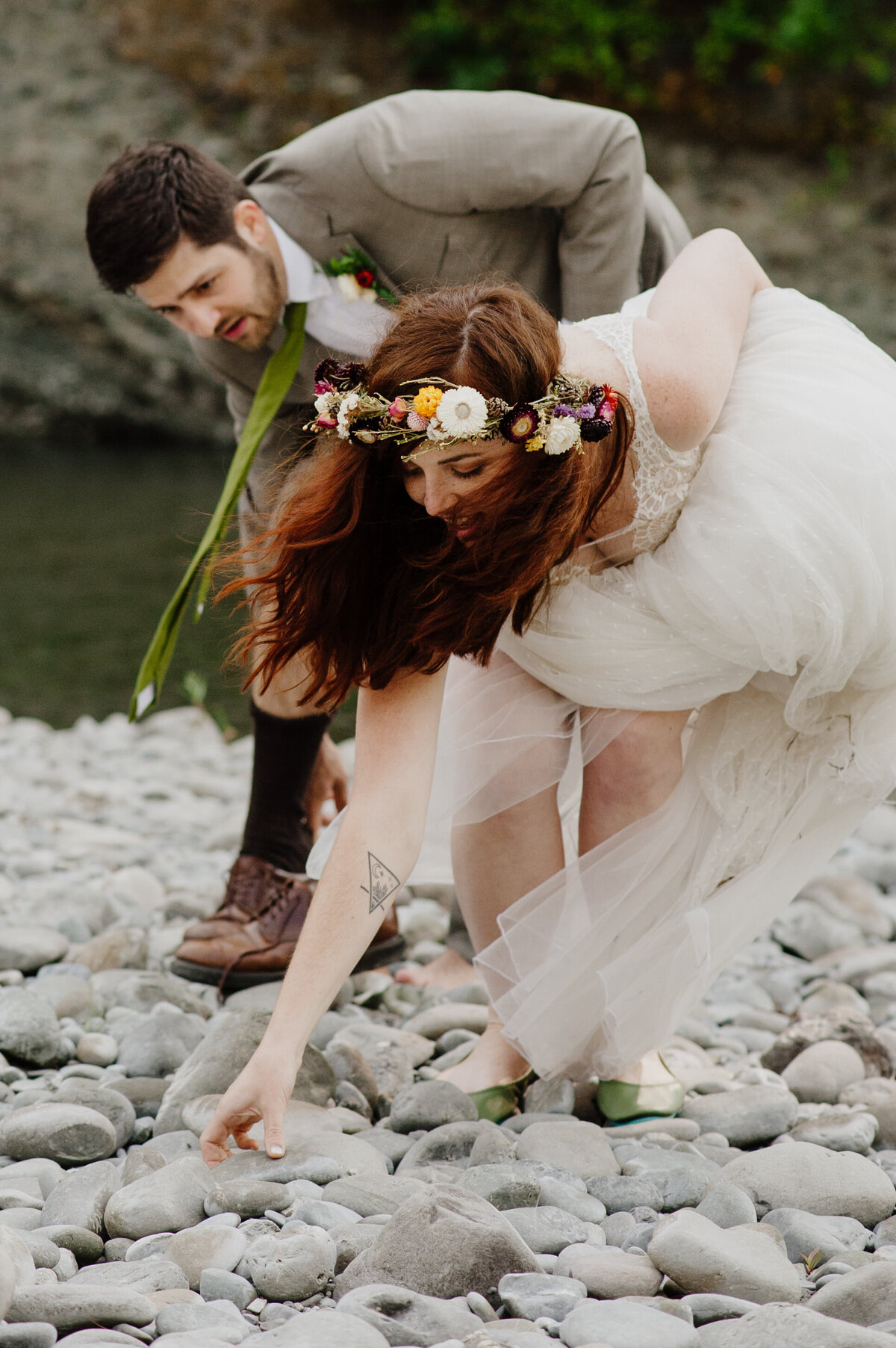 Bride and groom collect heart rocks from the riverbed at their Pamplin Grove redwood wedding