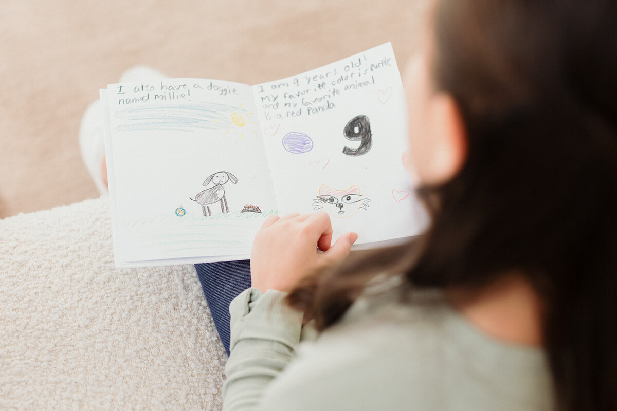 child looking through her drawing at therapist office