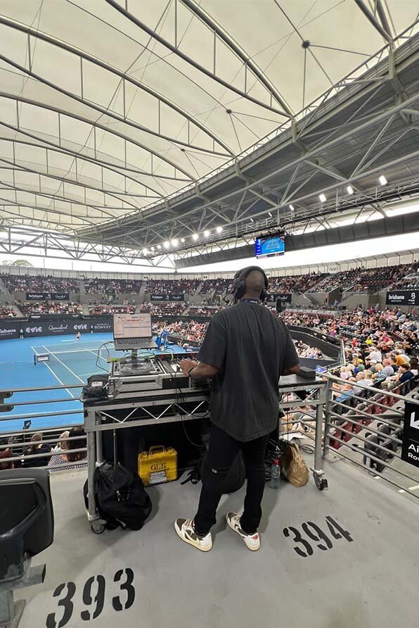 DJ mixing music from an elevated position above the court at a crowded United Cup tennis match